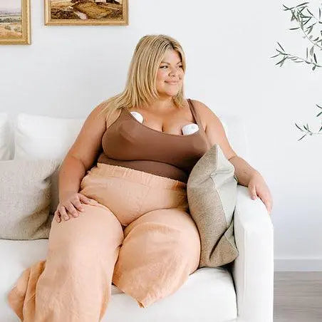 New mother using hands-free wearable breast pump while relaxing, showing postpartum mental health recovery and breastfeeding support journey