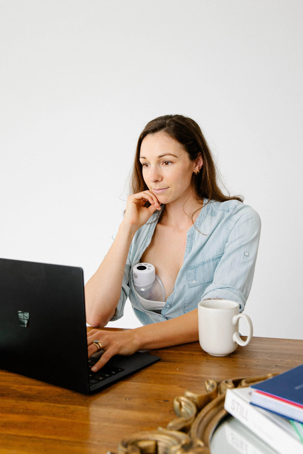 Busy Australian mother using Night Owl wearable breast pump while working, showing hands-free pumping convenience for active lifestyle